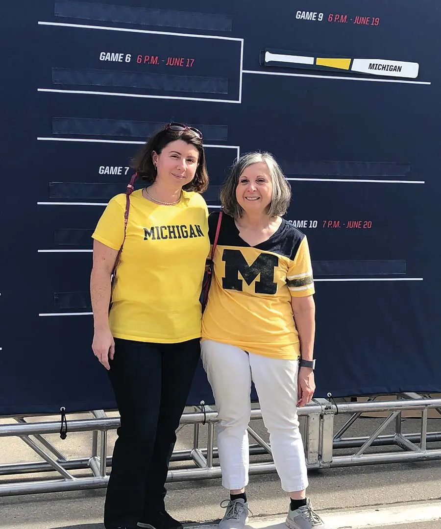 Two women posing together in front of sign