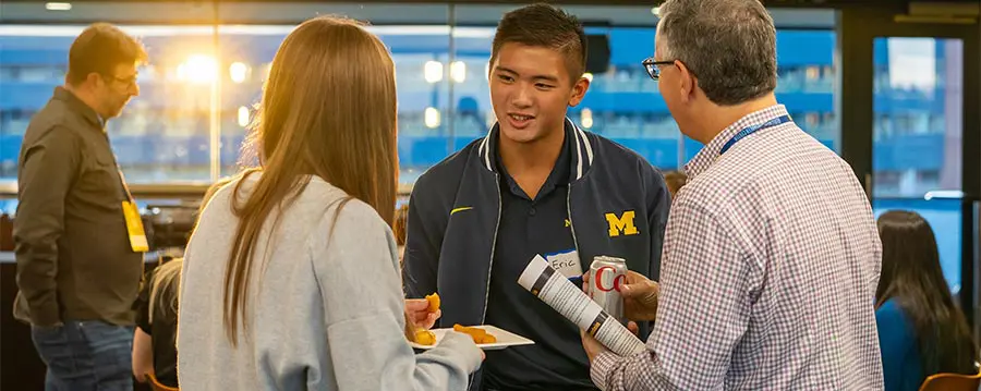 student-athlete talking to a man and woman