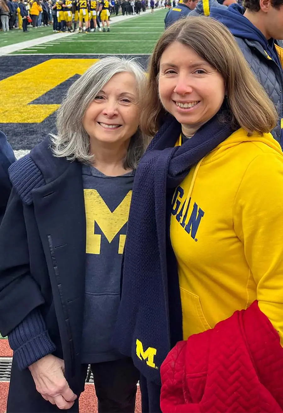 Two women posing together on a football field
