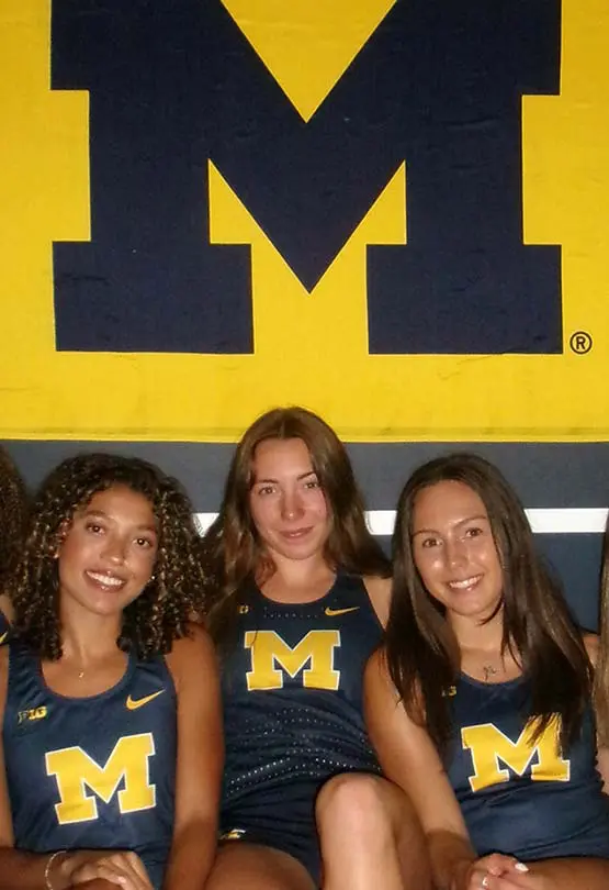 Group of women posing for photo in front of 'M' block