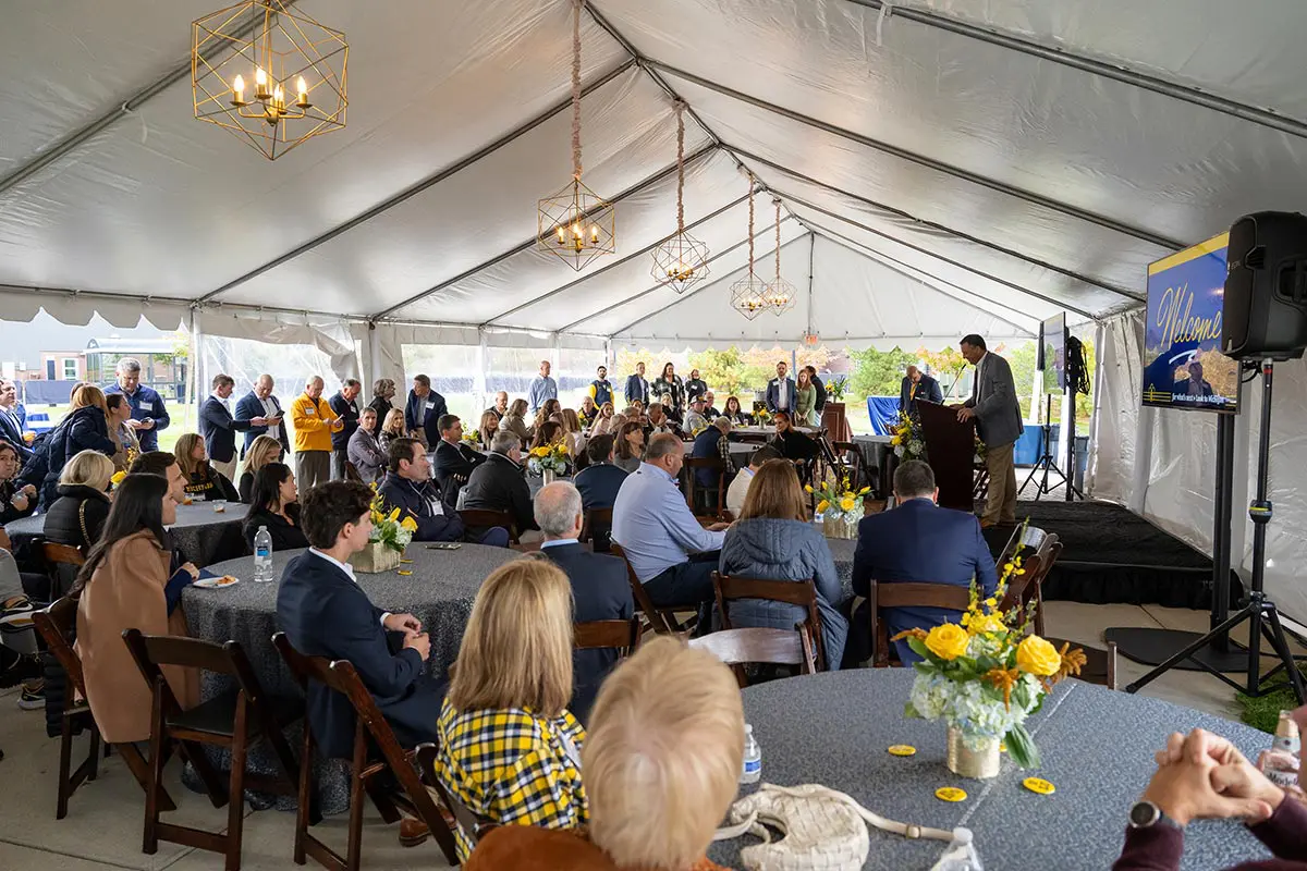 crowd sitting at tables listening to man speaking